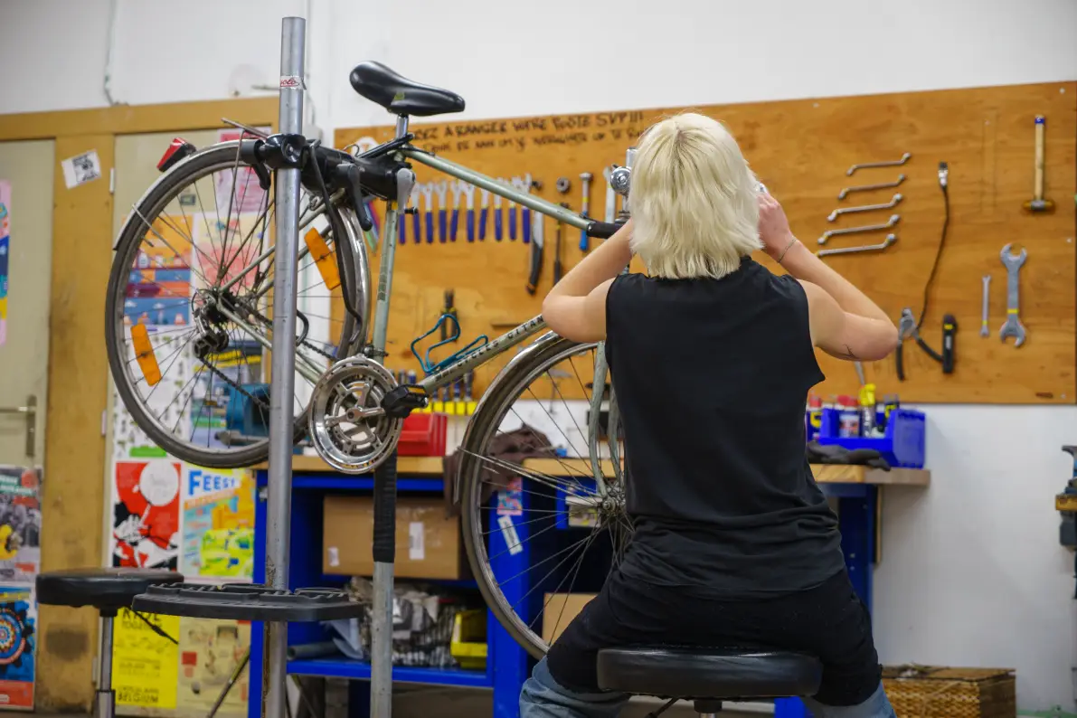 Une personne répare un vélo de dos